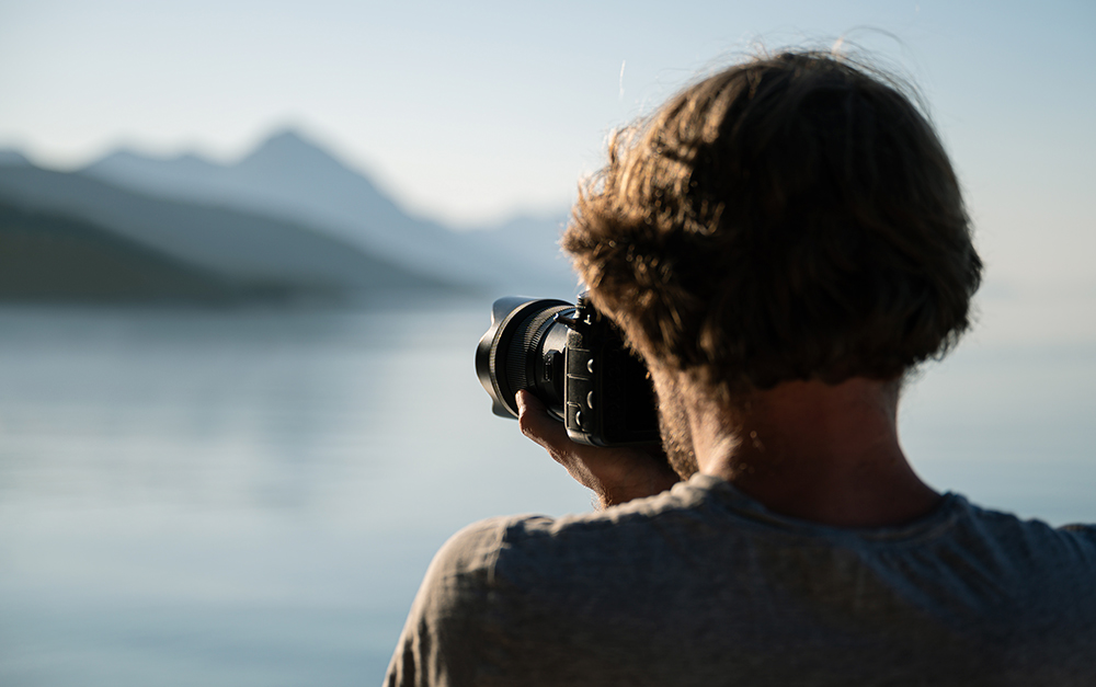 A imagem mostra um homem tirando fotos da paisagem.