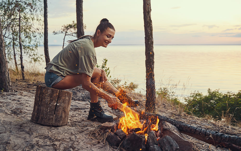 A imagem mostra uma mulher aproveitando a sua viagem de acampamento.
